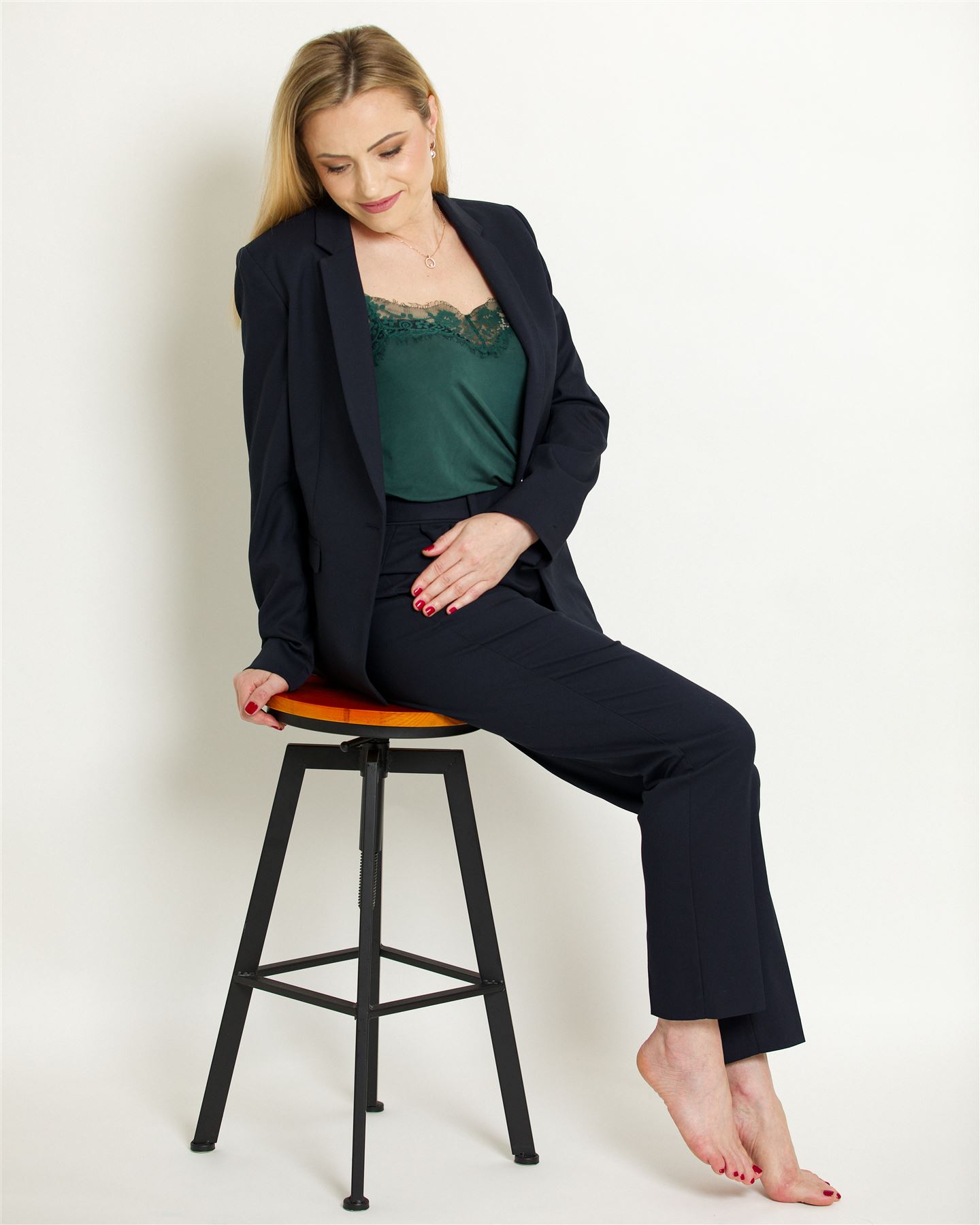 Aliona sitting on a bar stool in a navy suit